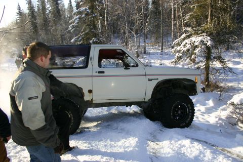 2003 Jeep TJ - White Ford Bronco II with large tires navigates a snowy trail.