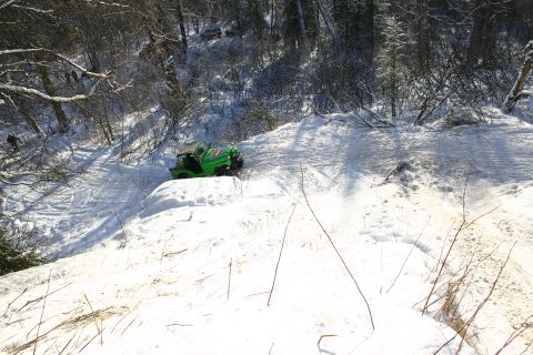2003 Jeep TJ - A green Jeep TJ navigates a snow-covered hill in a wooded area.