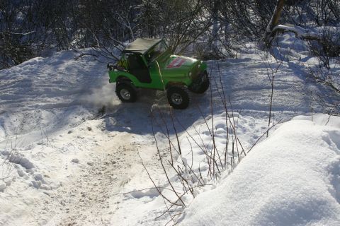2003 Jeep TJ - Off-road vehicle navigates a snowy trail, leaving tracks in the snow.