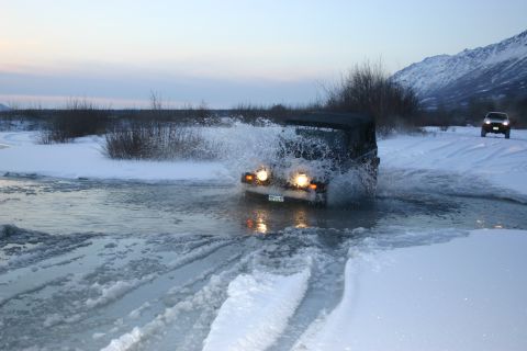 2003 Jeep TJ - Jeep TJ navigating a water crossing in a snowy landscape with another vehicle visible in the distance.