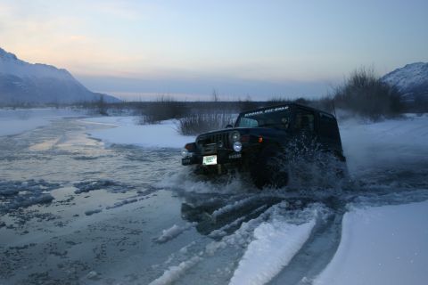 2003 Jeep TJ - Jeep TJ navigates icy water crossing in a snowy landscape.
