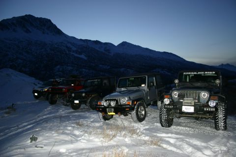 2003 Jeep TJ - Several Jeeps are parked in a snowy landscape with mountains visible in the distance.