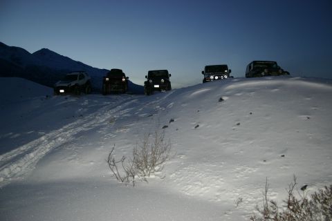 2003 Jeep TJ - Multiple off-road vehicles navigate a snowy incline under a twilight sky.