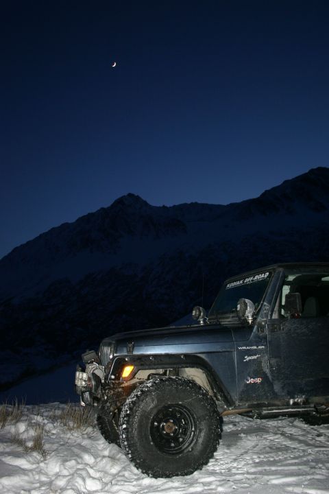 2003 Jeep TJ - Jeep TJ Wrangler Sport in a snowy mountain scene at dusk with a crescent moon visible.
