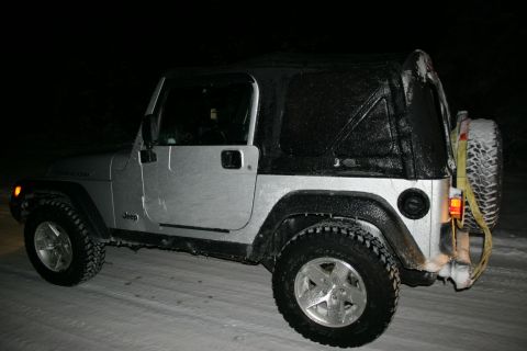 2003 Jeep TJ - A Jeep Wrangler is parked on a snow-covered road at night, with ice coating its exterior.