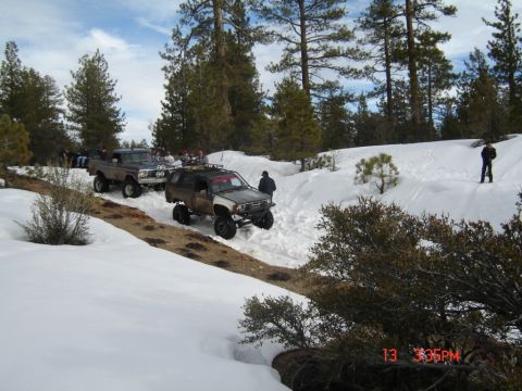 2000 Ford F-450 - Several off-road vehicles navigate a snow-covered trail in a wooded area.