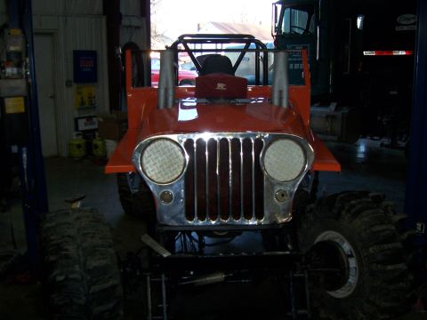 1999 Jeep TJ - This heavily modified Jeep is parked inside a garage with a large truck in the background.