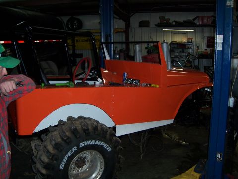 1999 Jeep TJ - Custom off-road vehicle with large tires and exposed engine bay is being worked on in a garage.