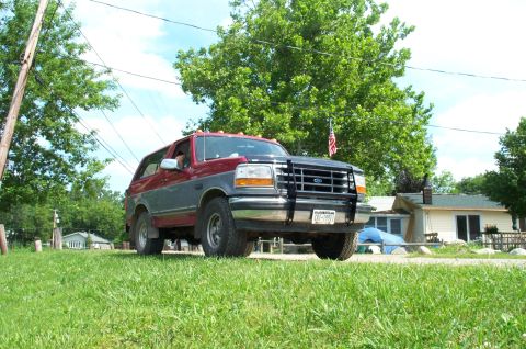 1995 Ford Bronco - 1995 Ford Bronco with a two-tone paint job and a brush guard is parked outside a house.