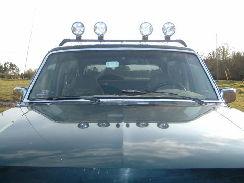 1993 Ford Bronco - Front view of a dark green Ford Bronco with auxiliary lights on the roof rack.