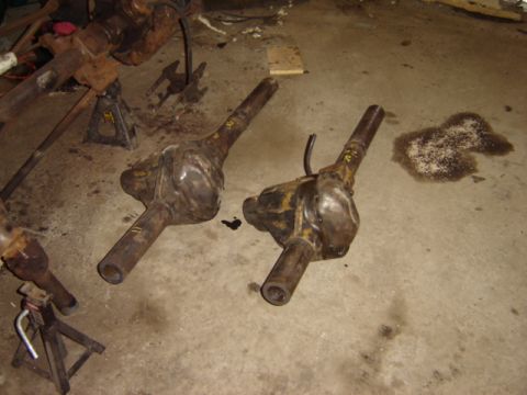 1992 Ford Bronco - Two rusty Ford Bronco rear axle assemblies are shown on a concrete floor, possibly in a garage or workshop.