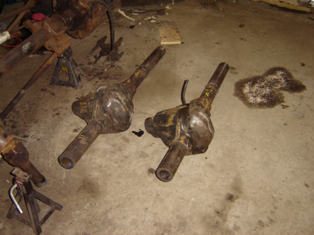 Two rusty Ford Bronco rear axle assemblies on a concrete floor