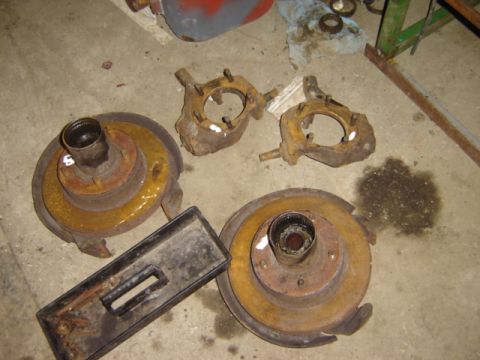 1992 Ford Bronco - Vehicle parts, including brake rotors and steering knuckles, are scattered on a concrete floor.