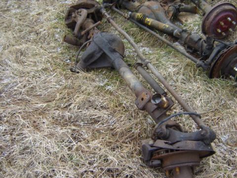 1992 Ford Bronco - Multiple rusty vehicle axles and suspension components lie on the ground.