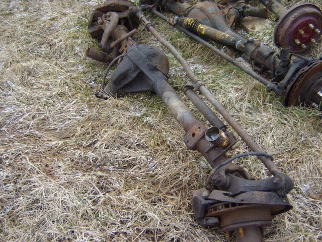 Rusty vehicle axles and suspension parts on dry grass