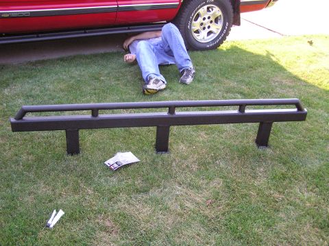 2000 Chevrolet Tahoe - A person works on a red Chevrolet pickup truck, with a new bumper laid out on the grass.