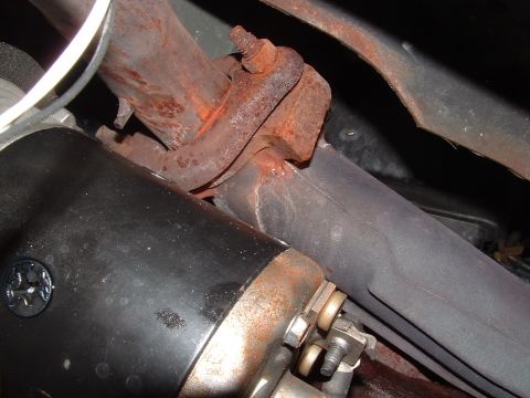 1989 Ford Bronco - Detail of a vehicle's exhaust system and starter motor, showing signs of rust.