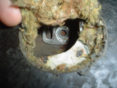 1993 Ford Taurus - A nut and bolt are visible through a hole in damaged insulation, suggesting a mechanical component.