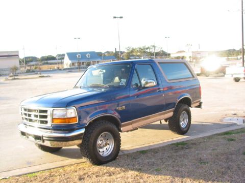 1996 Ford Bronco - A blue 1996 Ford Bronco is shown from a three-quarter front angle in a parking lot.
