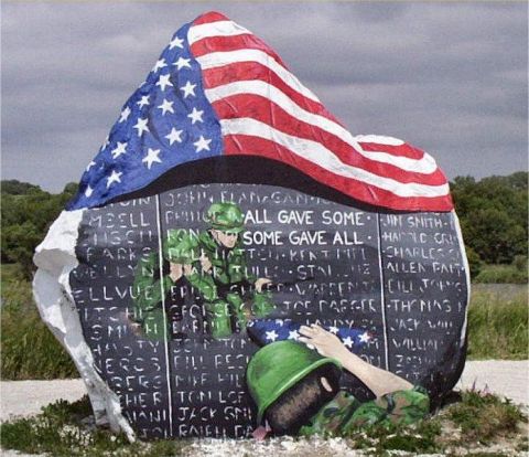 1991 Ford Bronco - A memorial rock displays names of fallen soldiers and painted figures of soldiers under a large American flag.