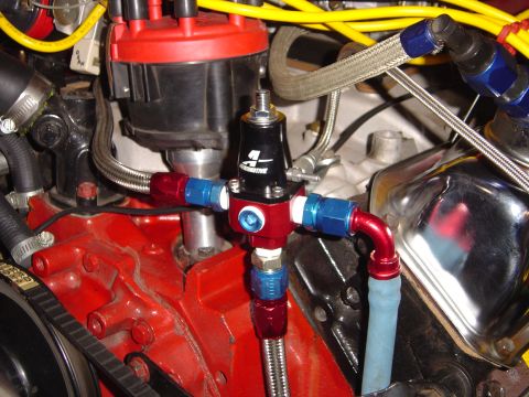 1978 Ford Bronco - Close-up of an Aeromotive adjustable fuel pressure regulator mounted at the front of a red-painted V8, plumbed with braided stainless lines…