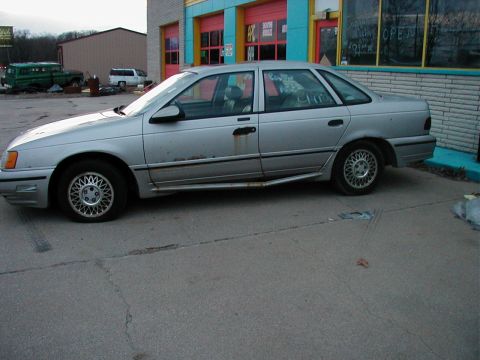 1997 Ford Taurus - This silver 1997 Ford Taurus sedan is seen from the side, parked in front of a colorful building.
