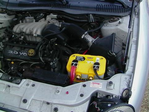 1999 Ford Taurus - The engine bay shows a 3.0 V6 engine and a yellow Optima battery, with a Supermotors.net watermark visible.