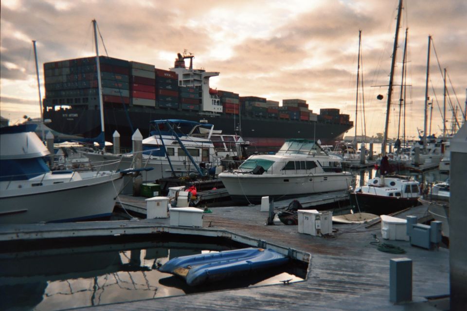 Marina full of boats with a large container ship passing behind at dusk