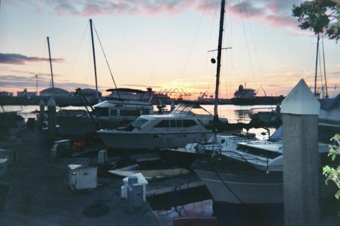 1990 Ford Bronco - Yachts sit in their slips at dusk under a pastel sky with distant harbor structures in silhouette.