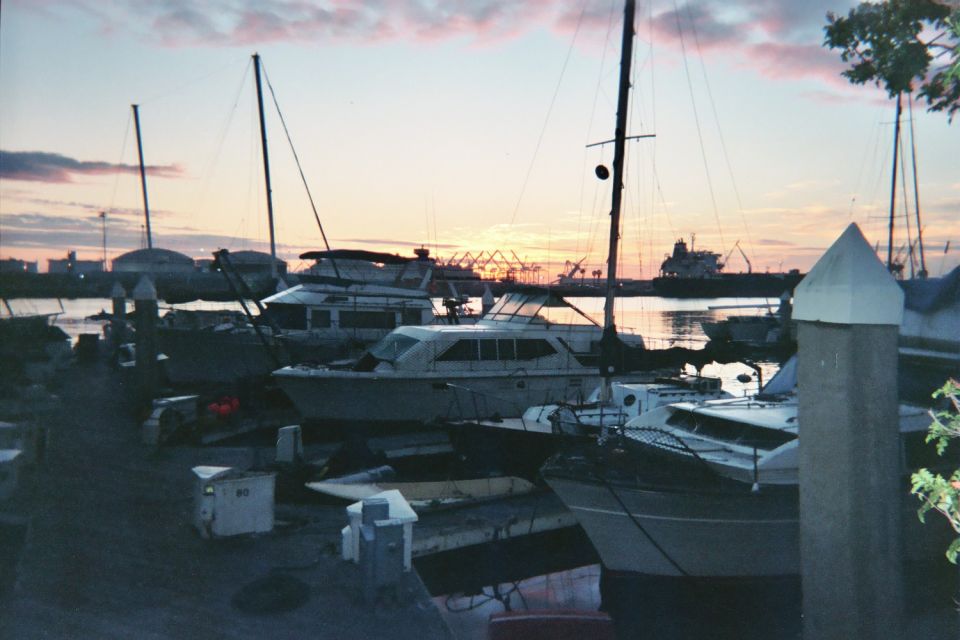 Marina of yachts at dusk with a pastel sky and distant harbor structures