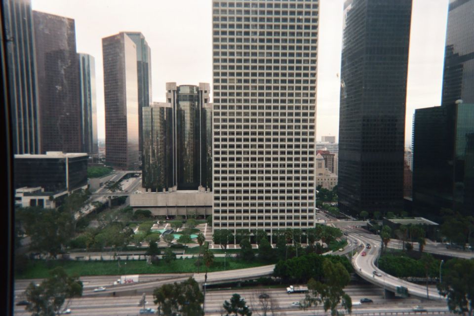 High window view of a gridded tower among downtown skyscrapers and freeway ramps