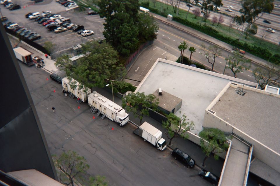 Aerial view of parking lots, a white tractor-trailer rig, and a box truck beside a flat-roofed building