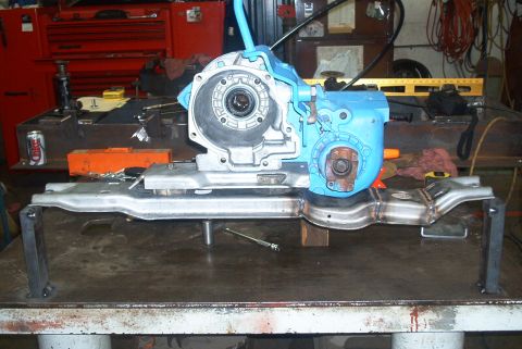 1983 Ford Bronco - A blue transfer case is mounted on a metal bracket, resting on a workbench with tools and a soda can visible.