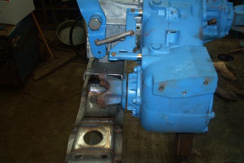 1983 Ford Bronco - Close-up view of a blue transfer case being mounted to a vehicle frame.