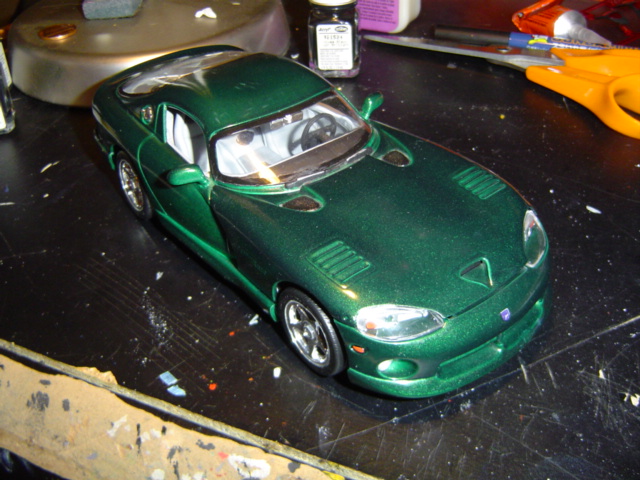 Green toy car on a workbench with craft supplies