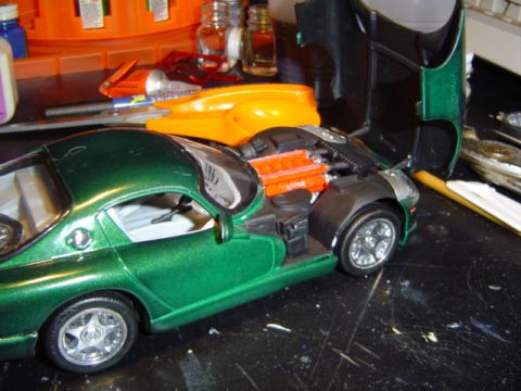 1979 Ford Bronco - A green model car sits on a black surface with various crafting supplies in the background.