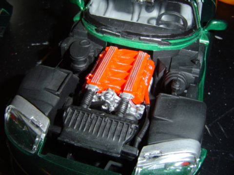 1979 Ford Bronco - A close-up view of the engine compartment of a green model car, highlighting its orange engine.