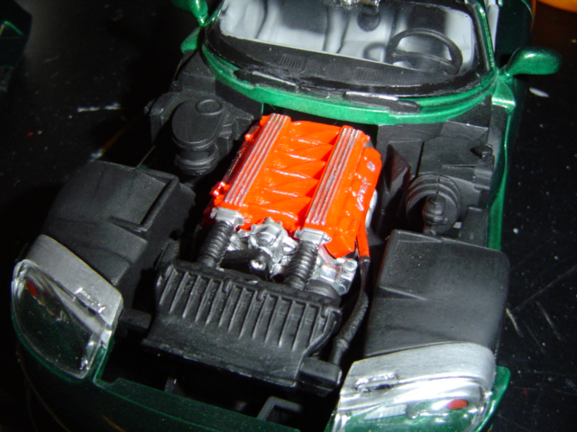 Green car model's engine bay with orange V-engine