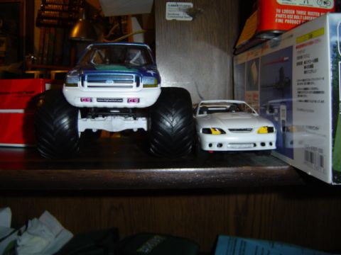 1979 Ford Bronco - Two toy vehicles are displayed on a shelf, one a large monster truck and the other a smaller sports car.