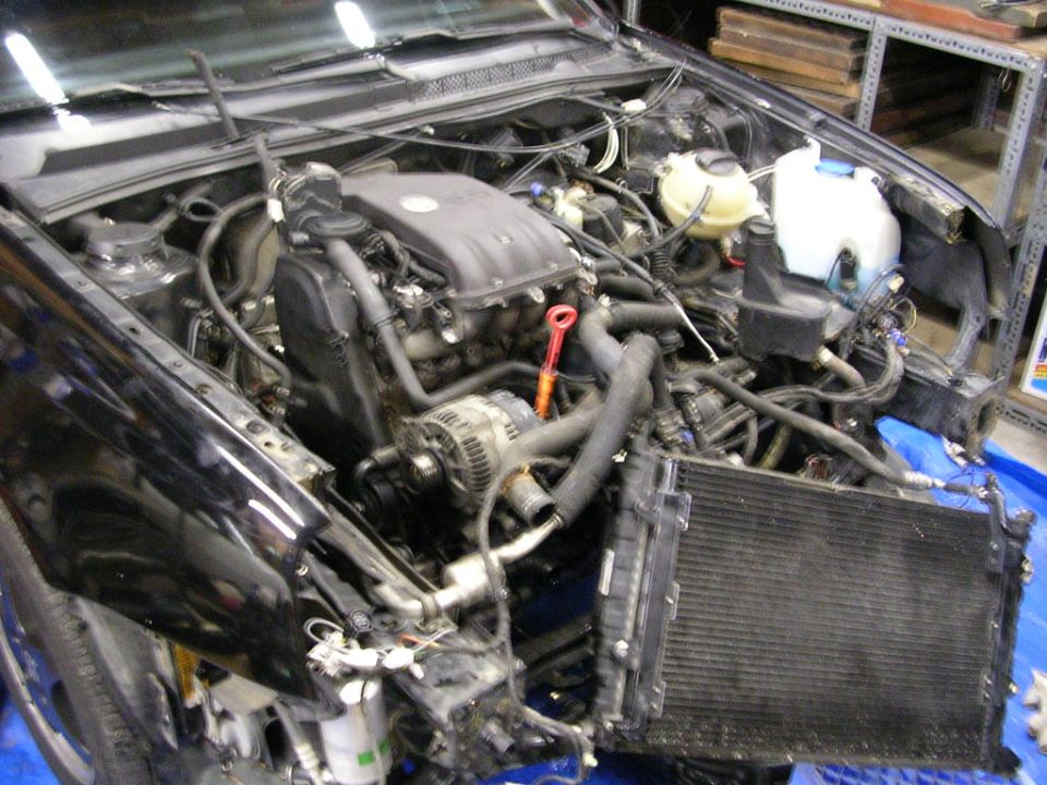 Volkswagen engine bay during swap with radiator hanging loose, red dipstick and loose wiring
