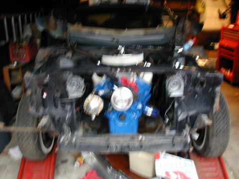 1968 Ford Mustang - The engine bay of a 1968 Ford Mustang shows a blue engine and exposed front end components.