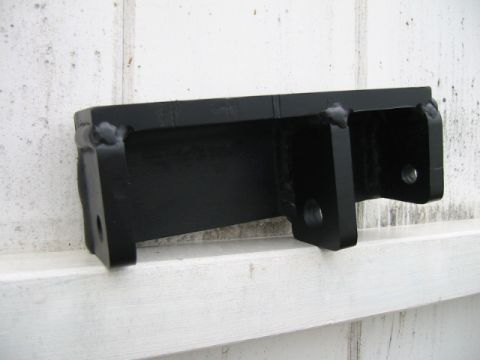 1992 Ford Bronco - A shop-fabricated steel bracket finished in gloss black, sitting on a white-painted wood ledge outdoors. It combines a channel section with…