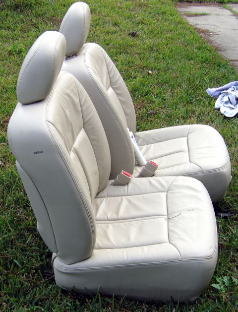 2000 Ford Crown Victoria - Two tan leather car seats with visible "AIRBAG" labels are placed on a grassy area.