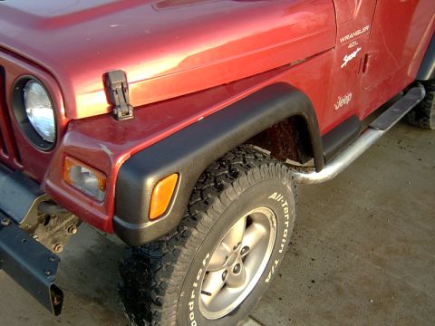 1998 Jeep TJ - A red Jeep Wrangler is shown from the front 3/4 view, highlighting its fender and tire with visible model badging.
