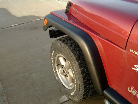 1998 Jeep TJ - Close-up view of the fender and tire on a red Jeep Wrangler, likely a 1998 model.