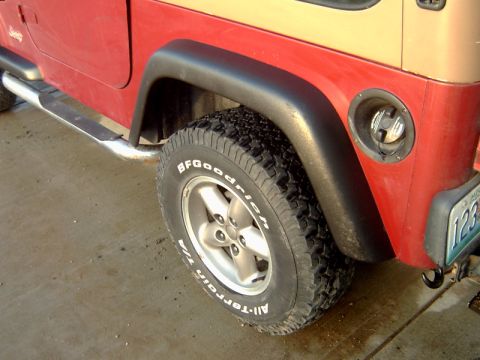 1998 Jeep TJ - Close-up of a Jeep TJ's rear side, showing the tire and fuel filler door.