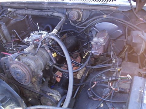 1985 Ford Bronco - View of the engine bay, the carburetor and brake fluid reservoir, with extensive wiring visible.