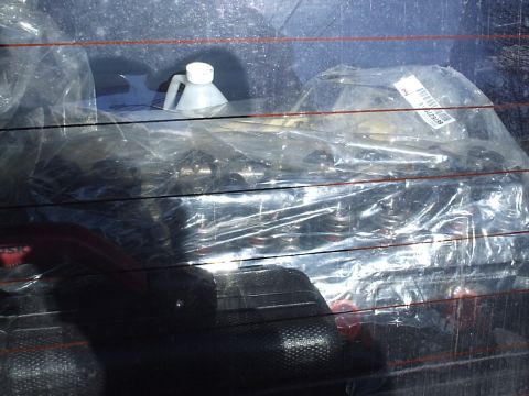 1985 Ford Bronco - Parts are wrapped in plastic and stored on the back seat of a vehicle.