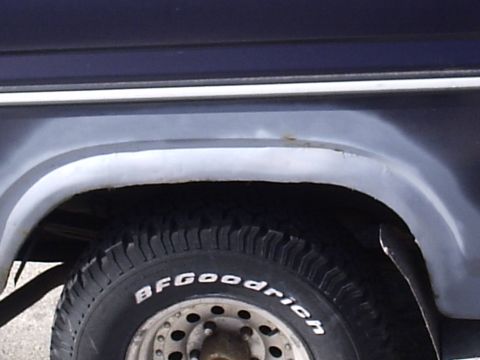 1985 Ford Bronco - The side of a vehicle shows a tire and wheel well with some rust visible on the fender.