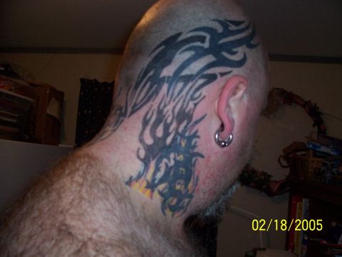 1989 Ford Bronco - A man displays extensive tribal tattoos covering his head and neck, including flame designs.